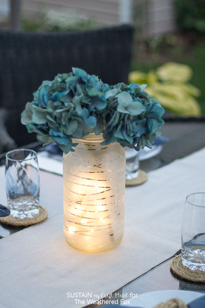 Learn how to upcycle a large glass jar to a gorgeous lantern centerpiece. Beautiful summer patio or wedding decor idea!