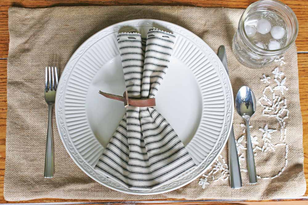 farmhouse table setting, ticking cloth napkin, leather napkin ring, burlap placemat, white plate 